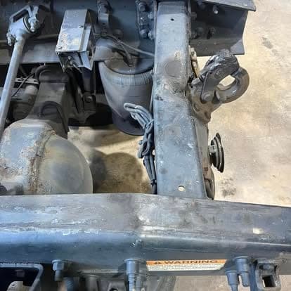 The underside of a truck showing the driveshaft, differential housing and rear frame rails during a driveline repair.