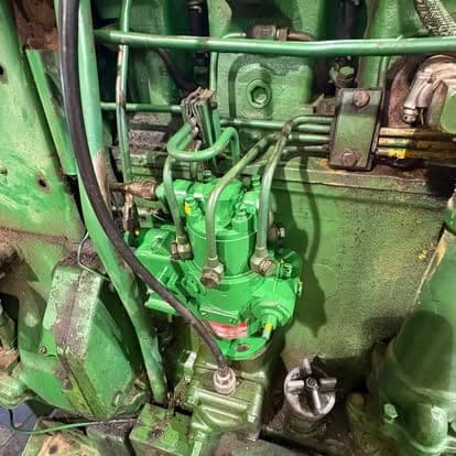 The inline fuel injection pump and hard fuel lines on a green John Deere tractor engine.