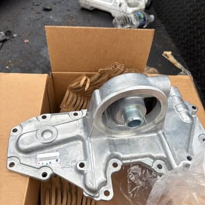 A new cast aluminum engine front cover still in its box, ready to go on during a rebuild.